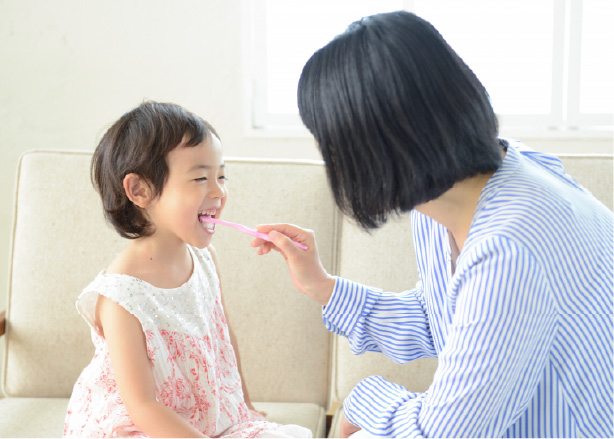 母親が子供の歯を磨いている画像